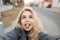 Funny young happy woman in a gray fashion coat makes selfie