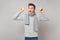 Funny young man in gray sweater, scarf fooling around showing tongue hold oranges isolated on greybackground. Healthy