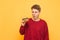 Funny young man holds a burger in his hands, looks at fast food with a surprised look, isolated on a yellow background. Hungry