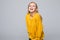 Funny young woman in yellow sweater, widely smiling,. Isolated on yellow background