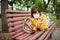 Funny youthful woman lies on her stomach in park bench with a protective mask