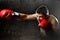 Furious man training boxing on gym with red fighting gloves throwing vicious punch