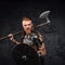 Furious redhead viking with axe on his shoulder looking at camera