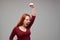 Furious young woman with auburn hair holding fist above