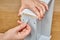 The furniture assembler puts a plastic pin into the hole on the surface of the wooden drawer with his thumb, with the other hand