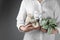 Furoshiki technique. Woman holding gifts packed in different fabrics decorated with plants on gray background, closeup