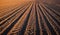 Furrows row pattern in a plowed field prepared for planting crops in spring.