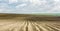 Furrows rows in a plowed field prepared for planting potatoes crops in spring.