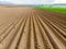 Furrows rows in a plowed field prepared for planting potatoes crops in spring.