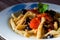 Fusilli al ferro with black olives and cherry tomatoes on wood background