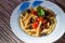 Fusilli al ferro with black olives and cherry tomatoes on wood background