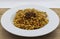 Fusilli Lunghi Bucati with bolognese sauce on a white plate, wooden table. Traditional italian pasta.