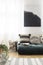 Futon with patterned cushions in natural living room interior with poster. Real photo