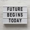 `Future begins today` words on a lightbox on a white wooden background, top view. Overhead, from above, flat lay. Closeup