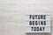 `Future begins today` words on a modern board on a white wooden background, top view. Overhead, from above, flat lay. Copy space