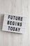 `Future begins today` words on a modern board on a white wooden surface, top view. Overhead, from above, flat lay