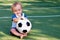 Future football star: Smiling infant with a soccer ball. Happy little boy at football field playing with ball