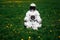 Futuristic astronaut in a helmet sits on a green lawn among flowersin a meditative position