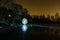 Futuristic glowing sphere on the surface of frozen lake at the background of night landscape