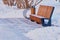 Futuristic wooden bench with an urn in a snowy winter park on a snow-cleared site.