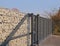 Gabion. Automatic entrance gate used in combination with a wall made of gabion