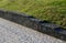 Gabion granite wall. wire baskets filled with stones. on the edge of the sidewalk, in the bend of the path, there is a low wall se