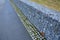 Gabion retaining walls with pipes for drainage water into the gutter by the road. wooden benches inserted, built into a dry wall i