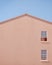 Gable house front view with pink wall and blue sky.Minimal concept.