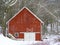 Gable roof closeup of red barn in winter snowstorm