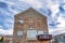 Gabled home with bay window balcony and stone brick wall against cloudy blue sky