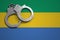 Gabon flag and police handcuffs. The concept of crime and offenses in the country