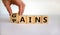 Gains and pains symbol. Businessman turns wooden cubes, changes word pains to gains. Beautiful white background. Business, pains