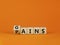 Gains and pains symbol. Turned wooden cubes, changed word pains to gains. Beautiful orange background. Business, pains and gains