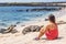 Galapagos tourist enjoying looking sitting by Galapagos Sea Lions