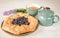 Galeta galette tart cake pie of whole grain flour with blueberries on a white country table with Turquoise color cup with flowers