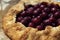 Galette with ripe red cherry on dark blue background. Homemade sweet open pie. Close-up