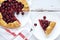 Galette with ripe red cherry filling on white wooden background. Homemade sweet open pie on Provence style background. Flat lay