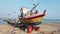 Galle, Sri Lanka - 2019-04-01 - two men work on dry docked small boat on beach - stem front