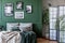 Gallery of black and posters and photos on emerald green wall in trendy bedroom