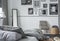 Gallery of black and white photos on wall of stylish bedroom interior with mirror, retro armchair and wooden table with blanket