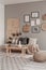 Gallery of black and white posters and wicker accessories on beige wall of Scandinavian living room