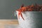 Galvanized steel bucket filled with boiled crawfish. Side view on wood table with copy space.