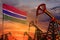 Gambia oil industry concept. Industrial illustration - Gambia flag and oil wells with the red and blue sunset or sunrise sky