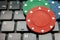 Gambling chips on computer keyboard on green background