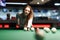 Gambling woman plays snooker in a billiards club