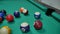 game of billiards with colored and numbered balls. 8 ball. green table and moving balls with billiard cue. panning the