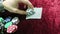 Game of poker. recounting the chips in his hand. lie around the chips. the game is on a red cloth velour table.