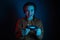 The gamer happy smiling woman with headphones and joystick playing video games on dark blue background. Neon colored