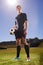 The games hero. Shot of a young footballer standing on a field with a ball in his hands.