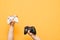 Gaming background. Two gamepads in the hands of a man on a yellow background. White and black joystick holds, isolated. Copyspace